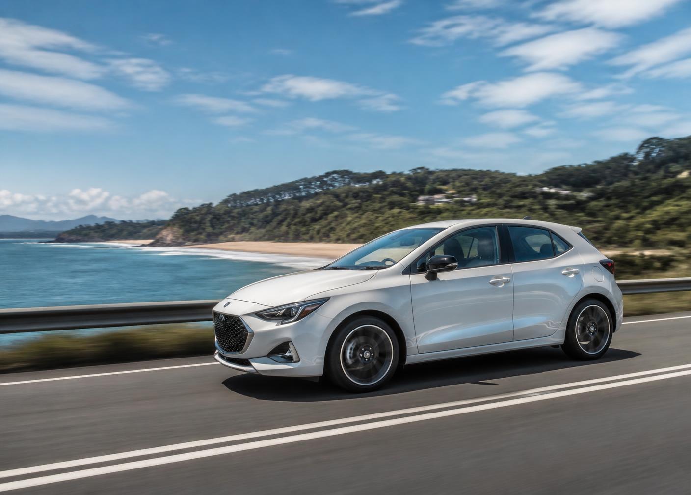 A modern hatchback driving on an open Queensland coastal road